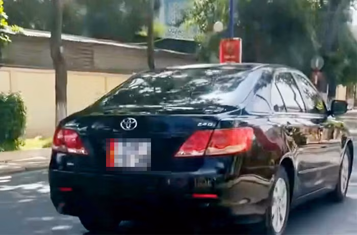 Bé gái ngồi trên người tài xế ôm vô lăng điều khiển xe ô tô bon bon trên đường -1