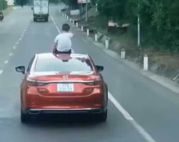 Nữ tài xế để con 9 tuổi ngồi trên nóc xe khi lưu thông trên đường -0