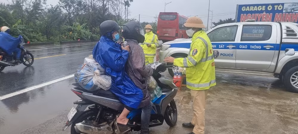 CSGT đội mưa tiếp đồ ăn, thức uống cho người dân trở lại miền Nam làm việc sau Tết -0