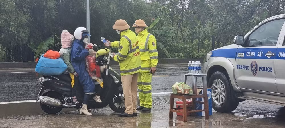 CSGT đội mưa tiếp đồ ăn, thức uống cho người dân trở lại miền Nam làm việc sau Tết -0