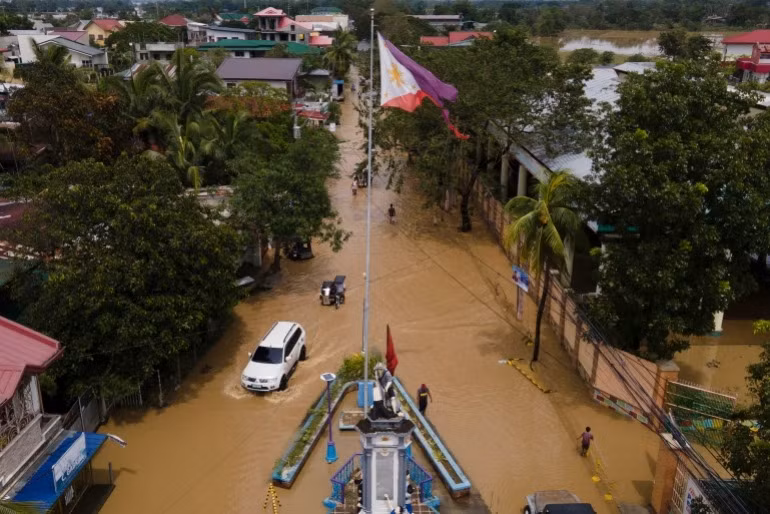 Người dân tại thị trấn San Miguel, tỉnh Bulacan, Philippines lội nước khi tham gia giao thông sau bão Noru. Ảnh AP.