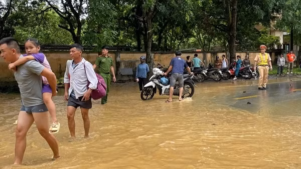 Công an huyện giúp dân di chuyển qua đoạn đường bị ngập do mưa lớn