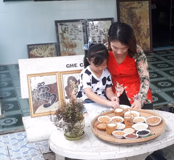 chị tuyết phượng hướng dẫn bé lâm yến nhi sáng tác tranh gạo. (ảnh trương anh sáng).jpg -0