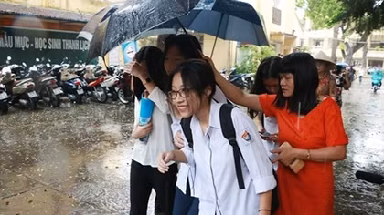Giám thị cầm ô che mưa cho thí sinh trong buổi thi cuối cùng