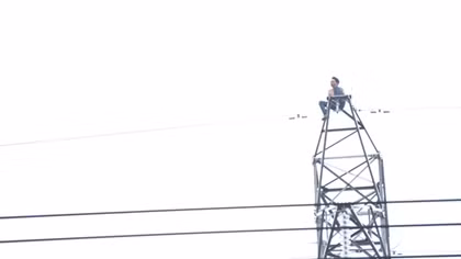 Nam thanh niên mình trần ngồi trên đỉnh cột điện cao thế la hét
