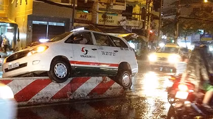 Tránh xe máy, taxi 'ngự' trên dải phân cách trong cơn mưa