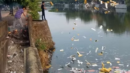 Hai người đàn ông rải vàng mã xuống sông Đông Ba gây ô nhiễm