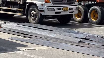 Xe đầu kéo thắng gấp, hàng chục tấm thép rơi trúng người đi đường