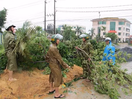 Cảnh sát 113 Công an Quảng Bình tỉa chặt cây cối, chằng chống nhà cửa giúp dân. (ảnh S.Lam).