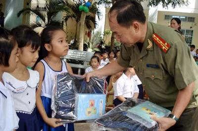 Đại tá Trần Kim Thẩm, Phó Tổng biên tập Báo CAND trao quà cho học sinh Trường Tiểu học Nguyễn Văn Trân.