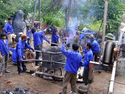 Các thợ đúc đồng đang rót mẻ đồng đầu tiên vào khuôn đúc lư đồng.