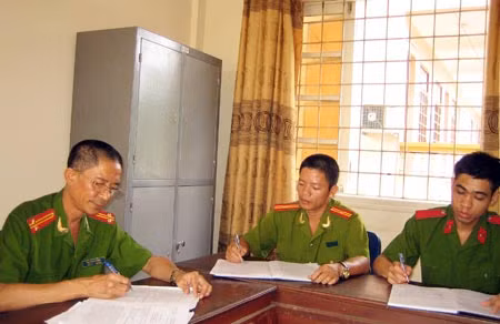 Trung tá Nguyễn Duy Sáng (người đeo kính) đang trao đổi hồ sơ án cùng đồng nghiệp.