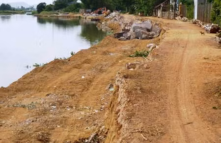 Các phương tiện cơ giới đã ủi sâu một phía của bờ kè để bỏ đá hộc, nhưng không có rào chắn, ban đêm không để đèn sáng báo hiệu, gây nguy hiểm đối với người qua lại (ảnh chụp sáng 26/7).