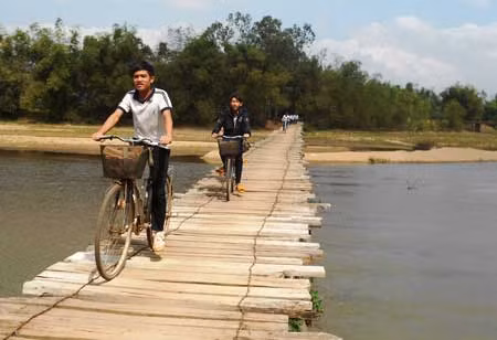 Mỗi ngày, học sinh đến được trường phải băng qua chiếc cầu sạp tạm bợ bằng gỗ. Ảnh: Hoàng Nguyên.