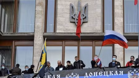 Những người biểu tình ủng hộ Nga treo biểu ngữ và phất cờ sau khi vào tòa nhà Chính phủ ở Donetsk.
