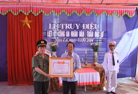 Đại tá Phạm Xuân Bình, Cục trưởng Cục Chính sách, Bộ Công an trao bằng Tổ quốc ghi công cho thân nhân Liệt sĩ Trần Đắc Lư tại UBND xã Ngọc Lũ, Bình Lục, Hà Nam. (Ảnh: Đỗ Mạnh Hùng).