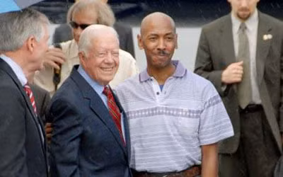 Cựu Tổng thống Mỹ Jimmy Carter và anh Aijalon Mahli Gomes chuẩn bị lên máy bay để về Mỹ. Ảnh: AP