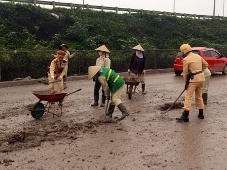 Những chiến sĩ CSGT Đội 14 đang cùng công nhân môi trường xử lý bùn đất trên đường, giúp người dân lưu thông an toàn hơn.
