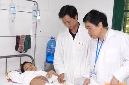 Bác sĩ Lương Nhất Việt (bên phải) thăm, khám bệnh cho cháu Tú.