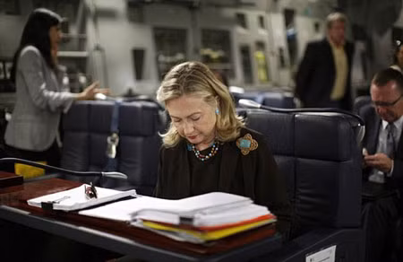 Bà hillary xem hồ sơ tại bàn làm việc khi máy bay C-17 chuẩn bị cất cánh từ Malta sang Tripoli.