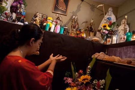Một phụ nữ cầu nguyện trước bệ thờ nữ Thần chết Santa Muerte.