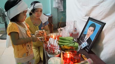 Vợ và con gái anh Hà bên bàn thờ chồng, cha.
