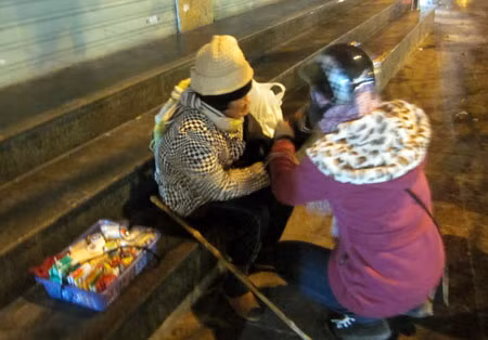 Một tình nguyện viên mặc áo ấm, đeo găng tay len cho cụ già...