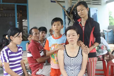 Người thân đang an ủi người mẹ mất 2 con (áo chấm bi, ngồi).