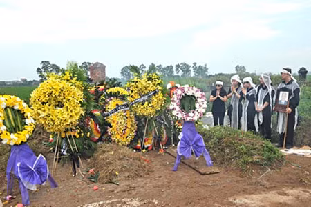 Gia đình ông Mai Trung Kiên bên phần mộ của ông.