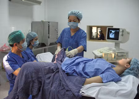 Tiến sĩ Quản Hoàng Lâm và các đồng nghiệp đang cấy phôi vào tử cung cho bệnh nhân.