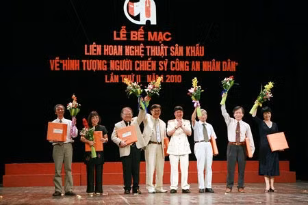 Anh hùng Lao động, Trung tướng, Nhà văn Hữu Ước - Phó Tổng cục trưởng Tổng cục XDLL CAND, Trưởng Ban Tổ chức Liên hoan tặng hoa và quà lưu niệm cho Hội đồng giám khảo. Ảnh: Trang Dũng.