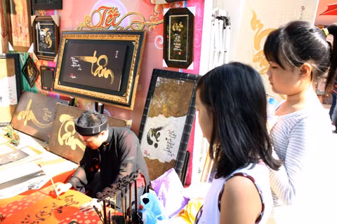 Đôi tay thoăn thoắt, nhanh nhẹn lướt đôi cọ với dòng mực đen trên nền giấy đỏ dưới ánh nắng Xuân. Đôi mắt của các em nhỏ như bị hút hồn trước sự điêu luyện của "ông đồ".