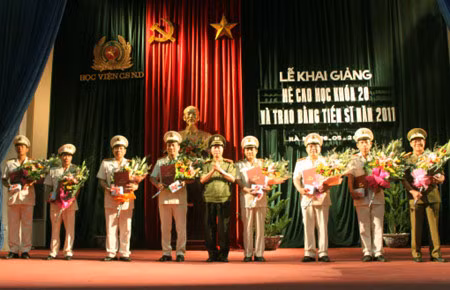 Thứ trưởng Bùi Văn Nam trao bằng và tặng hoa chúc mừng các tân tiến sỹ.
