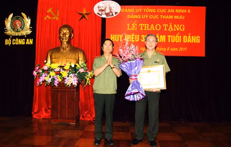 Thay mặt Đảng ủy Công an TW và lãnh đạo Bộ Công an, Trung tướng Đặng Văn Hiếu, Ủy viên TW Đảng, Phó Bí thư Đảng ủy Công an TW, Thứ trưởng Thường trực trao Huy hiệu 30 năm tuổi Đảng và tặng hoa chúc mừng đồng chí Trần Đại Quang, Ủy viên Bộ Chính trị, Bí thư Đảng ủy Công an TW, Bộ trưởng Bộ Công an. Ảnh: Công Gôn.