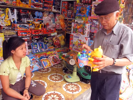 Bác Minh đang chọn mua đồ chơi gấu xiếc cho cháu ngoại mới 1 tuổi trên phố Chả Cá.