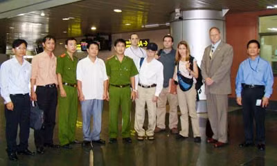Cảnh sát Interpol Việt Nam trao trả David (đội mũ, đứng thứ 6 từ trái sang) tại sân bay Nội Bài.