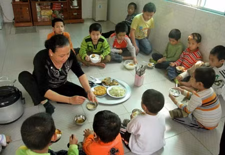 Mẹ nuôi Lê Thị Thu đang chia cơm cho các con.