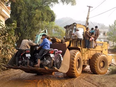 Đoạn đường vào mỏ bị ngập bùn, máy xúc được huy động để đưa dân qua suối.