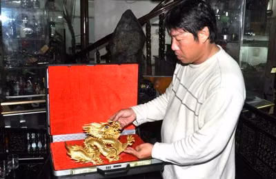 Nghệ nhân Trần Văn Anh với tác phẩm rồng vàng điêu khắc, chạm trổ tinh vi.