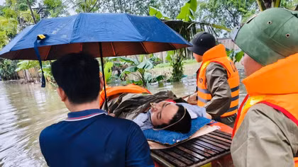 Cảnh sát dùng xuồng vượt khu vực ngập đưa người bị liệt đi cấp cứu