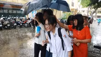 Giám thị cầm ô che mưa cho thí sinh trong buổi thi cuối cùng