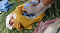 Bé trai sơ sinh trong túi nilon treo trên xe máy bên đường
