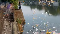 Hai người đàn ông rải vàng mã xuống sông Đông Ba gây ô nhiễm