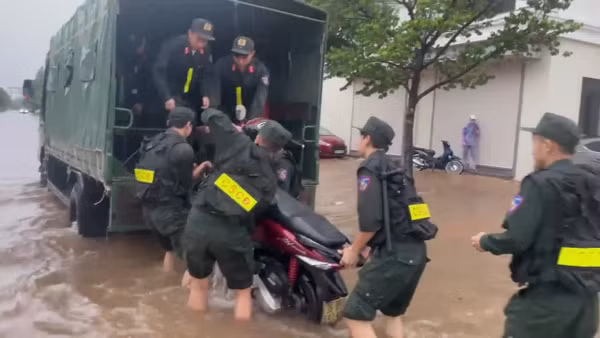 Cảnh sát cơ động hỗ trợ người dân di chuyển qua vùng ngập nước