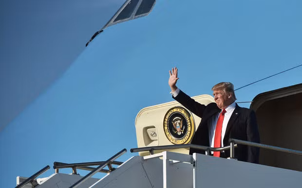 Tổng thống Donald Trump đứng vẫy tay ở cửa chuyên cơ Air Force One. Ảnh: ITN