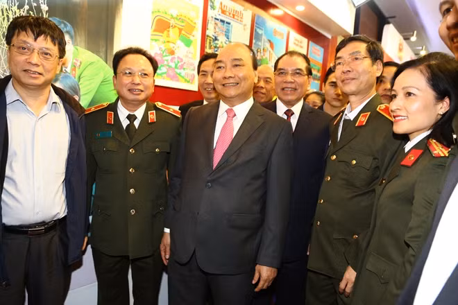Lãnh đạo Cục Truyền thông CAND giới thiệu tới Thủ tướng Nguyễn Xuân Phúc và nguyên Tổng Bí thư Nông Đức Mạnh các ấn phẩm, loại hình báo chí của lực lượng CAND.