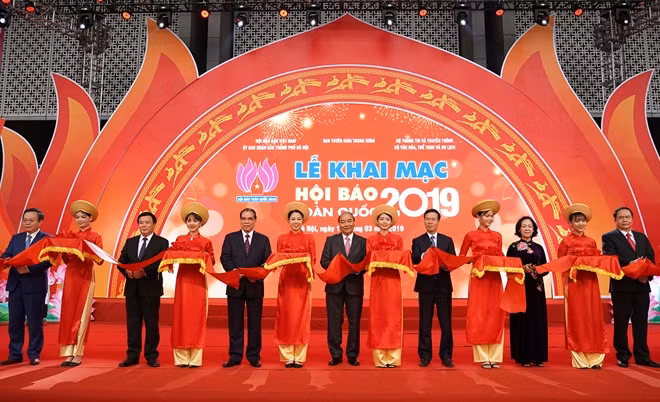 Thủ tướng Nguyễn Xuân Phúc, nguyên Tổng Bí thư Nông Đức Mạnh cùng các đồng chí lãnh đạo cắt băng khai mạc Hội báo Toàn quốc 2019.