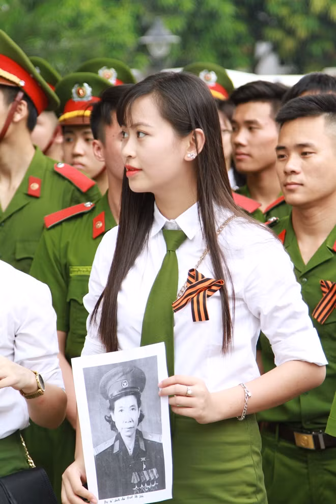 Một nữ sinh học viện Cảnh sát nhân dân cầm di ảnh của người thân trong lễ diễu hảnh "Trung đoàn Bất tử" năm 2017.