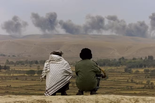 Tuy nhiên, khi Mỹ và các đồng minh NATO bắt đầu rời khỏi Afghanistan. Taliban mới cho họ hiểu là lực lượng này không hề bị đánh bại, chúng thậm chí còn tái phát triển mạnh mẽ và đe doạ nghiêm trọng chính quyền Afghanistan đương nhiệm. Trong ảnh là 2 người đàn ông Afghanistan nhìn về phía cao nguyên, nơi Taliban bị liên quân quốc tế tấn công bằng bom.