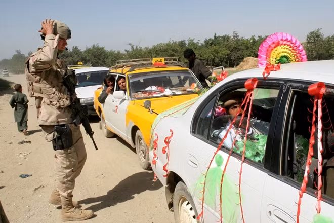 Đúng 2 tháng sau, ngày 7-12-2001, chế độ Taliban được tuyên bố đã sụp đổ hoàn toàn, khi mà các tay súng của lực lượng này đã buộc phải bỏ trốn khỏi pháo lũy phòng thủ cuối cùng bởi sự vượt trội về quân sự tới từ siêu cường Mỹ và đồng minh. Tuy nhiên, Mỹ đã không kịp hiểu rằng đây mới là màn khởi động cho cuộc chiến thực sự trên lãnh thổ Afghanistan. Trong ảnh là một binh lính Mỹ bên đoàn xe đám cưới tại Afghanistan năm 2005.